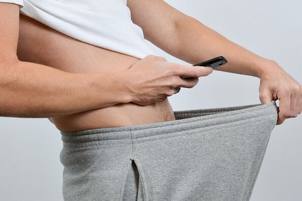 Usa ka tawo ang nagtan-aw sa iyang karsones sa usa ka gipadako nga penis